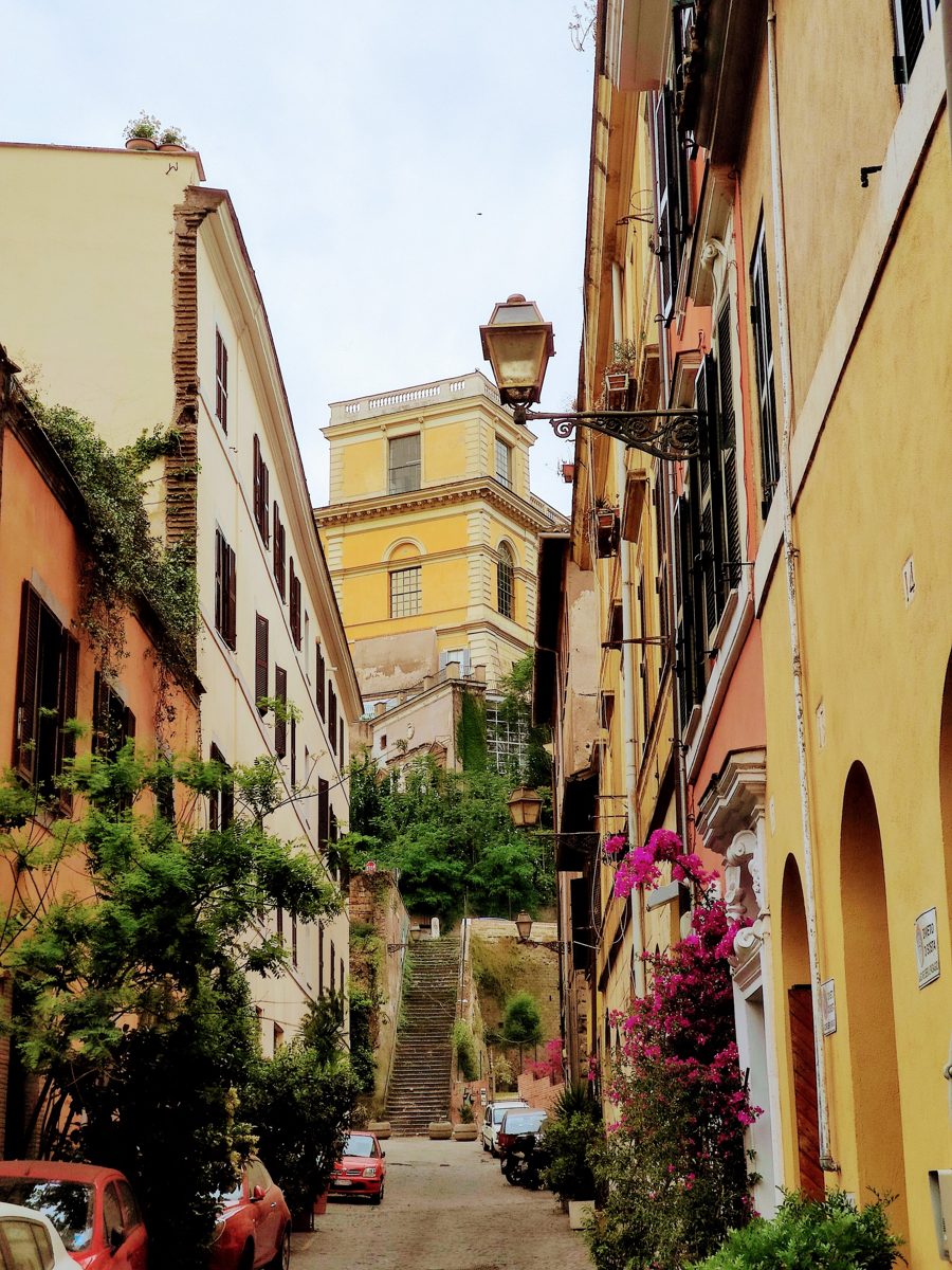 Narrow Trastevere street with ochre buildings and greenery