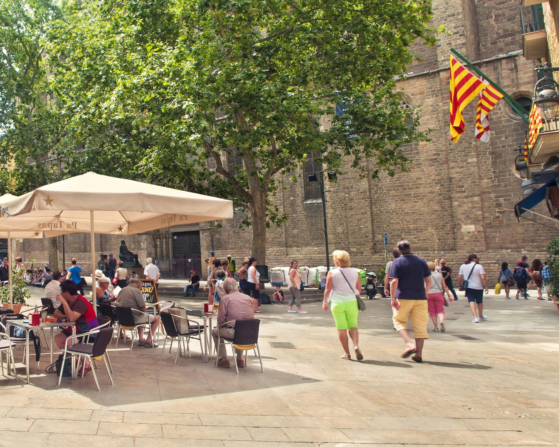 Outdoor café scene in Spain with people walking and relaxing on a sunny plaza