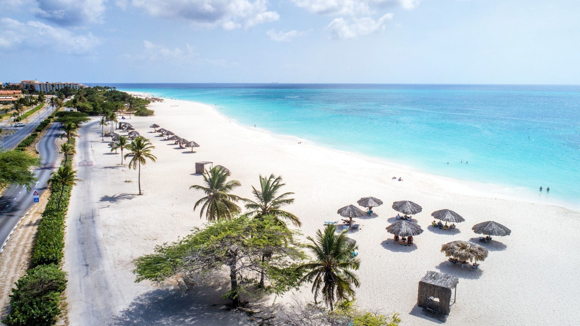 Aerial view of Eagle Beach in Aruba with white sand, turquoise water and palapas along the shoreline