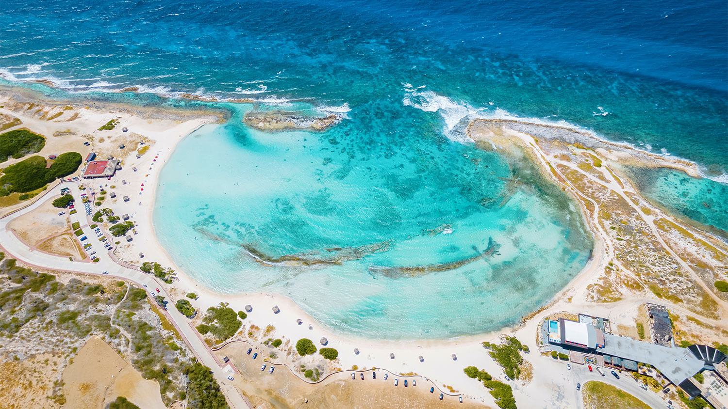 Aerial view of Baby Beach in Aruba with shallow turquoise lagoon and white-sand shoreline
