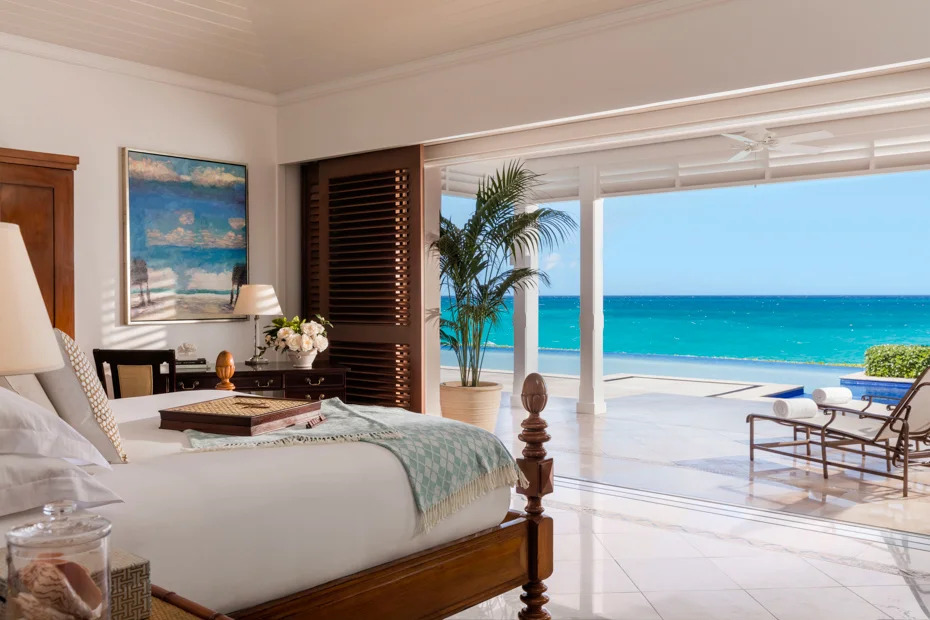 Luxury oceanfront hotel room in the Bahamas with open terrace, lounge chairs and turquoise sea view