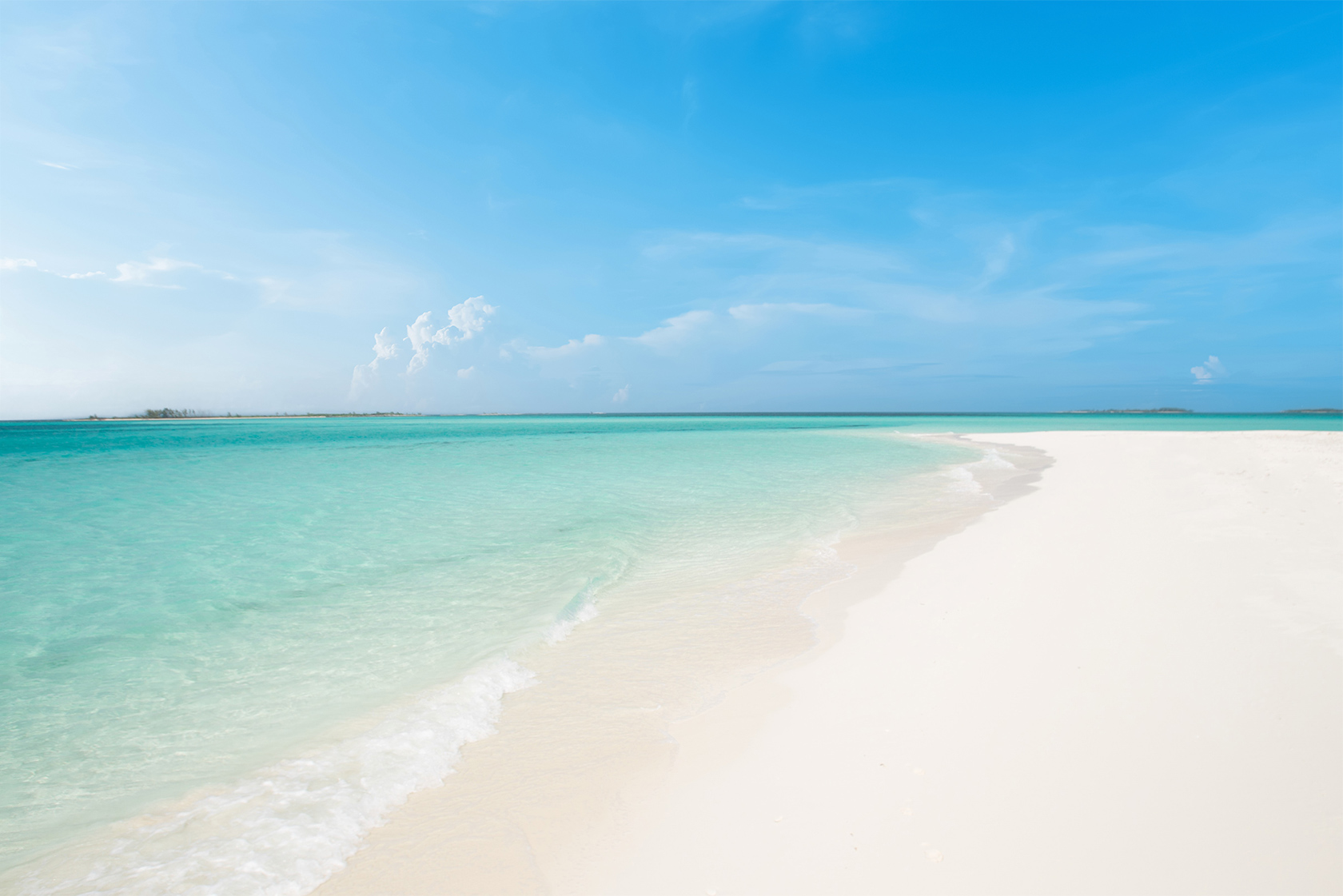 Pristine white-sand beach in the Bahamas with calm turquoise water and clear blue sky