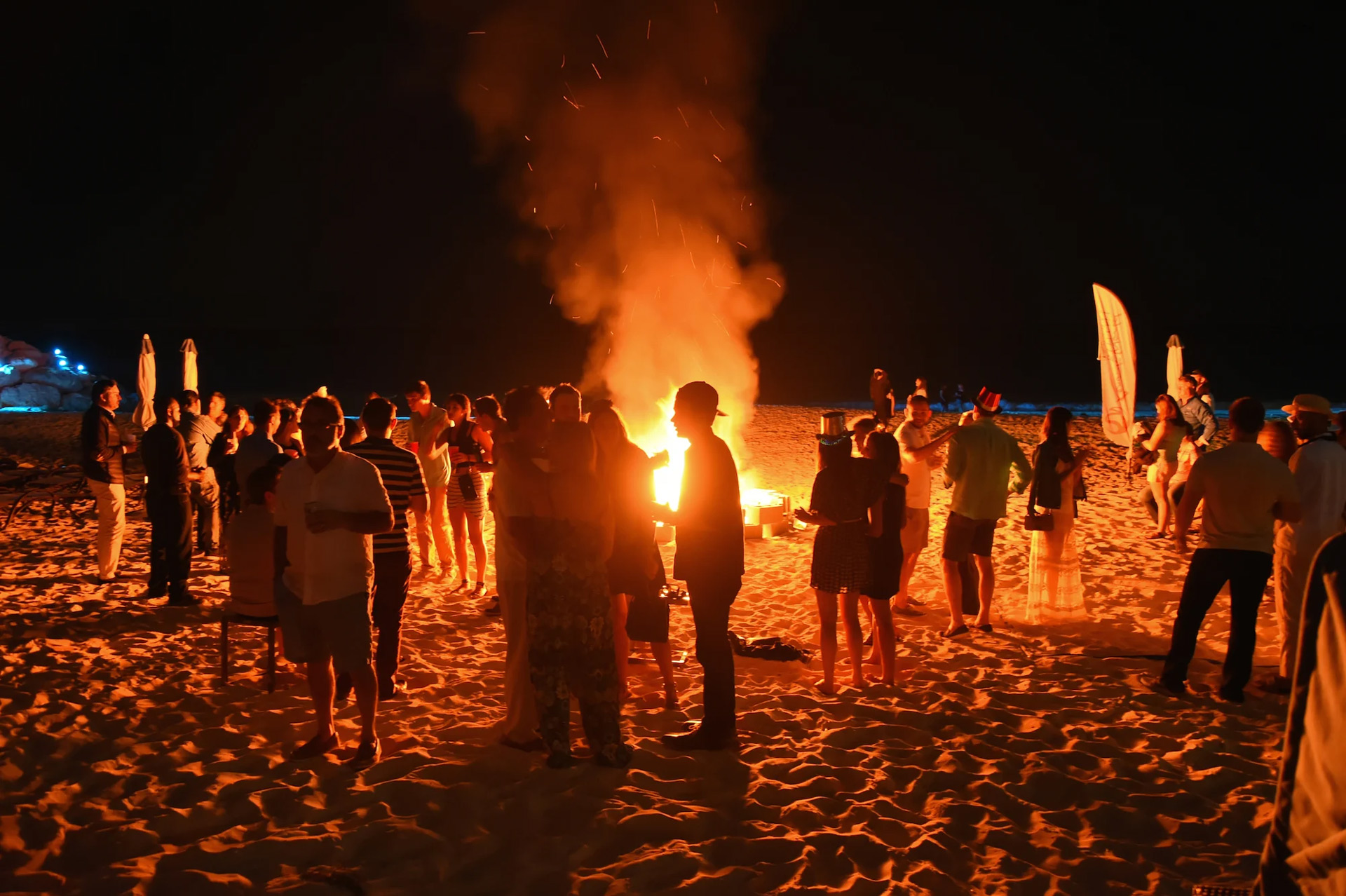 Beach bonfire party at night in the Bahamas with people enjoying music and tropical nightlife atmosphere