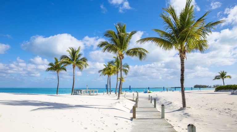 Sunny tropical beach in the Bahamas with white sand, palm trees and turquoise sea under a blue sky