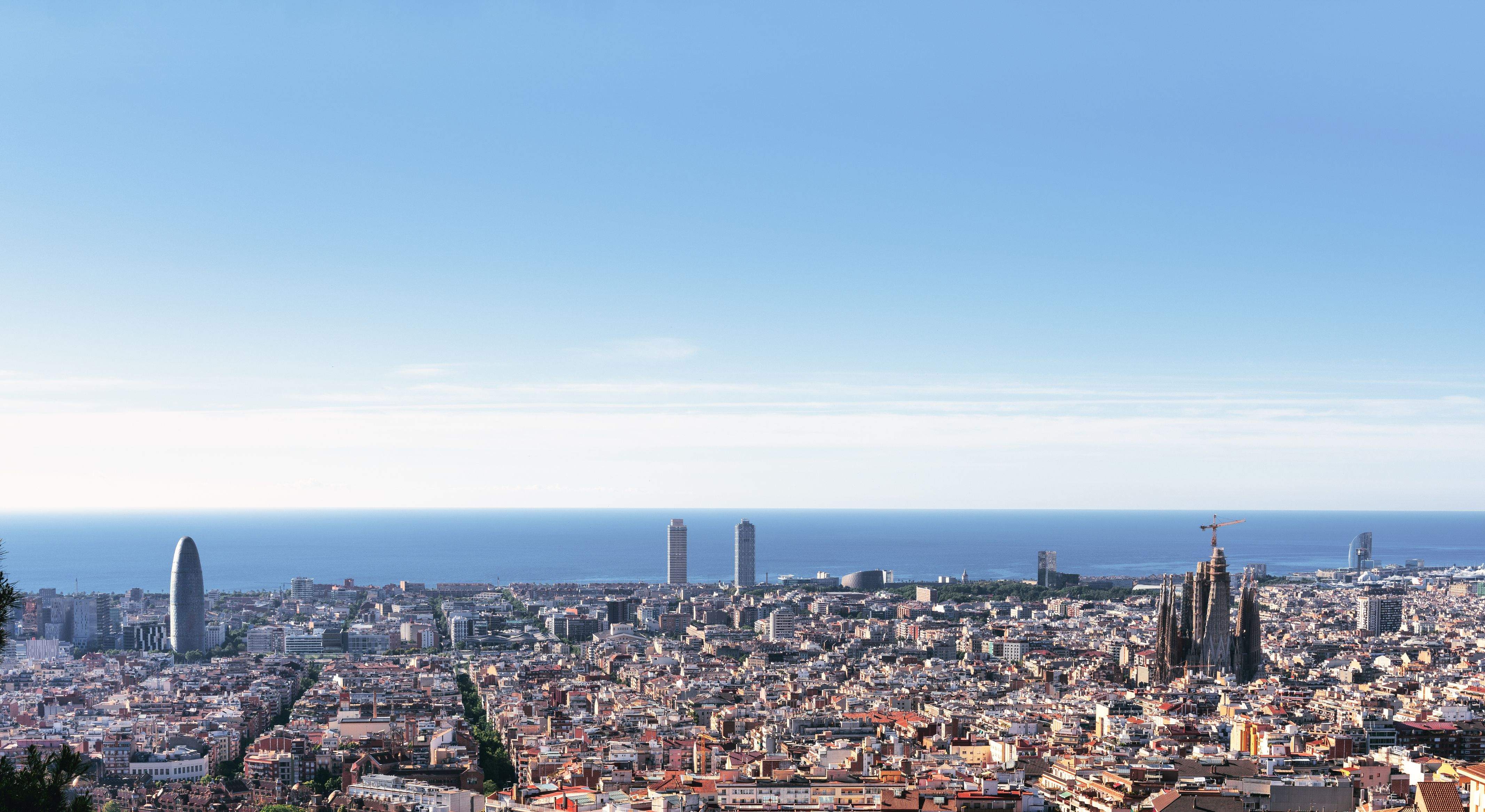 Panoramic view of Barcelona with Sagrada Familia, the Mediterranean Sea and the modern city skyline under a clear sky