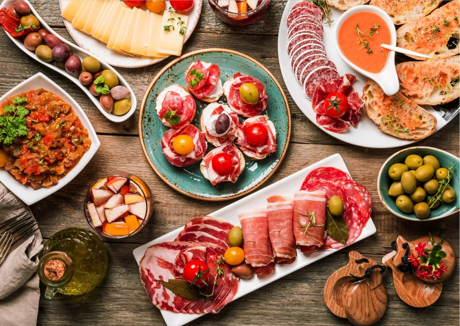 Barcelona Food & Drinks – Authentic Tapas, Local Flavors and Mediterranean Cuisine Traditional Catalan tapas selection with cured meats, cheeses, olives, pan con tomate and sangria on a rustic wooden table