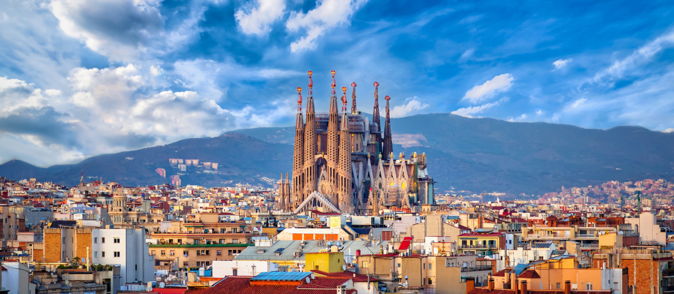 View of Sagrada Familia rising above Barcelona’s city rooftops with hills in the background