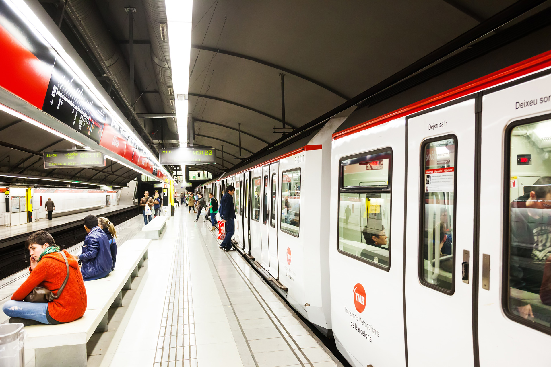 Barcelona metro train arriving at a modern underground station with passengers waiting on the platform