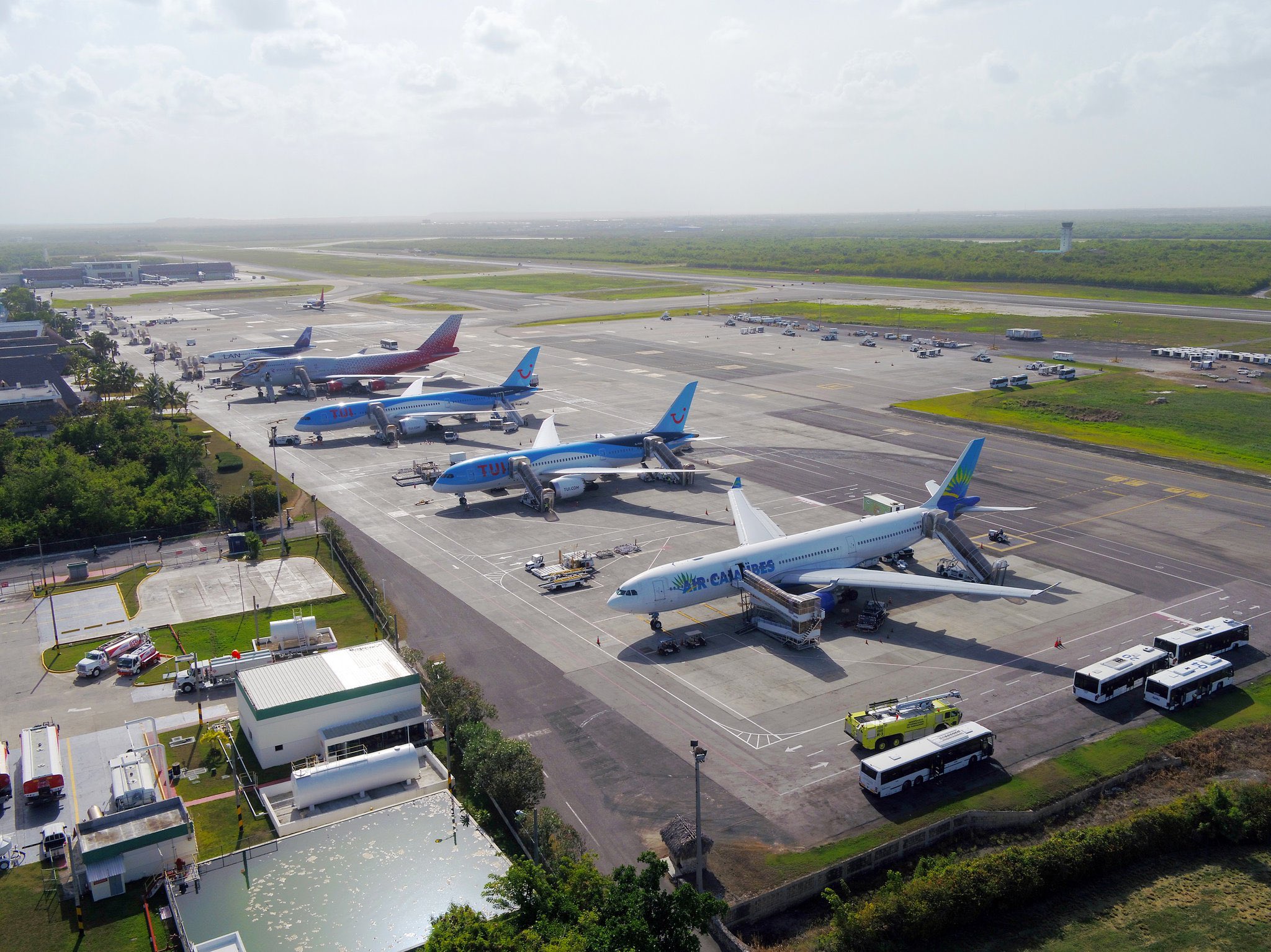 Aerial view of Punta Cana International Airport apron with multiple aircraft parked at the terminal under clear tropical skies