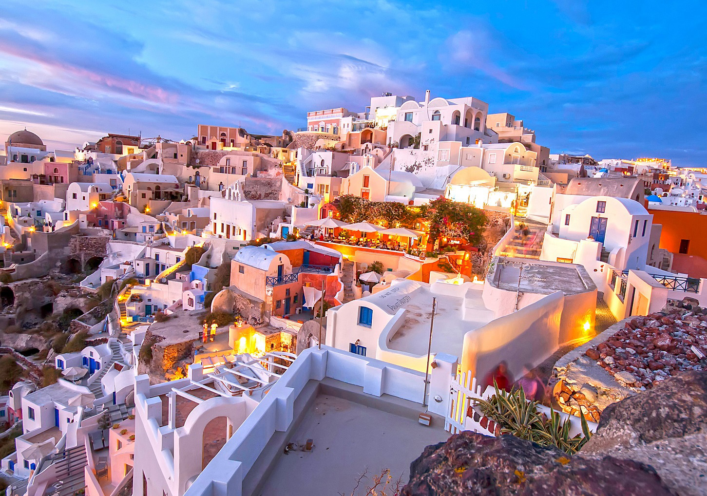 Evening view of Santorini in Greece with illuminated white buildings and blue-hour sky