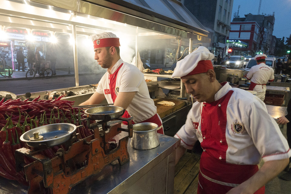 Cooks preparing Adana kebab on skewers