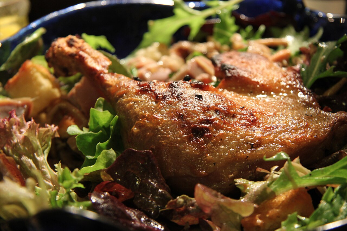 Confit de canard served on a salad, illustrating the duck dish and its crisped skin.