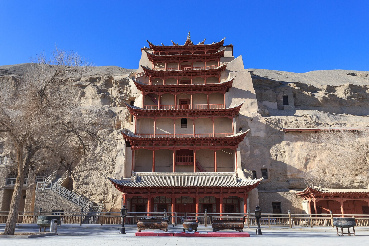 Red multi-storey temple facade against the Mogao cave cliff Red multi-storey temple facade against the Mogao cave cliff