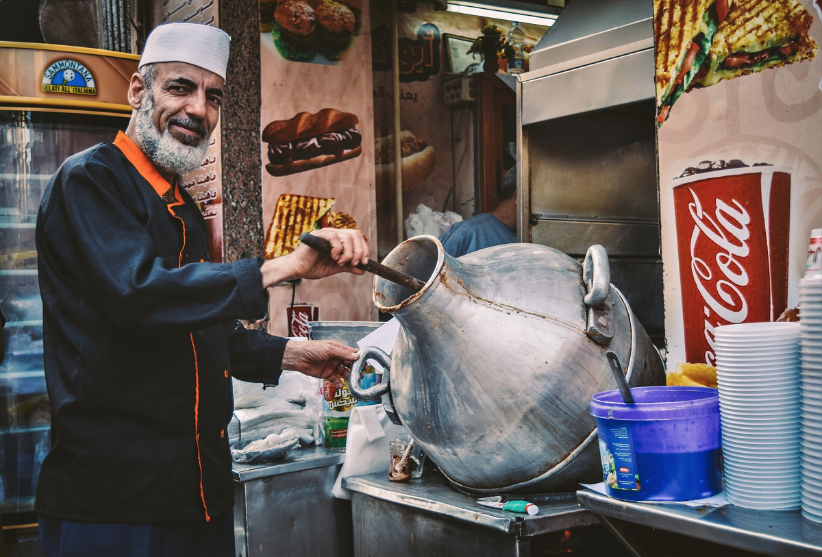 Street vendor serving ful medames from a large pot Street vendor serving ful medames from a large pot