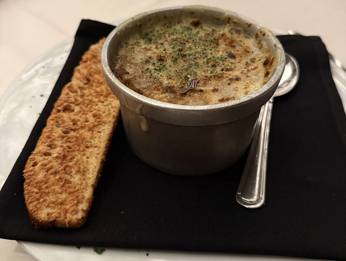 French onion soup with a browned topping, shown as a dish illustration rather than a named Paris restaurant’s current serving.