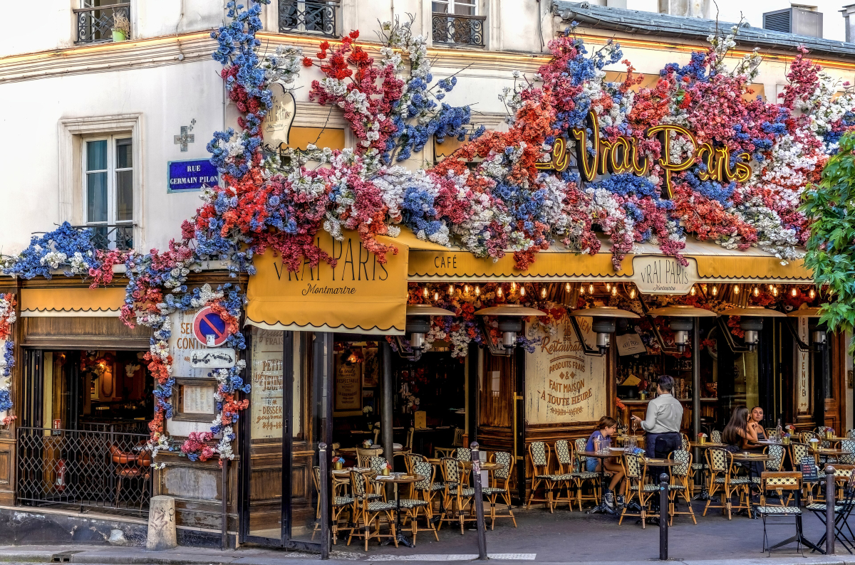 The decorated Le Vrai café frontage in Montmartre, photographed in August 2024; businesses and displays can change.