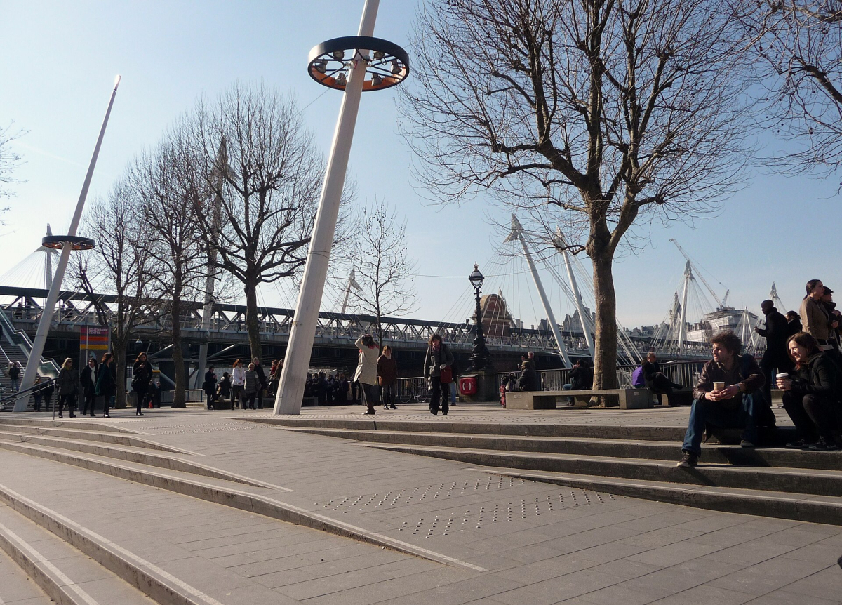 People walking along the South Bank of the Thames in London People walking along the South Bank of the Thames in London