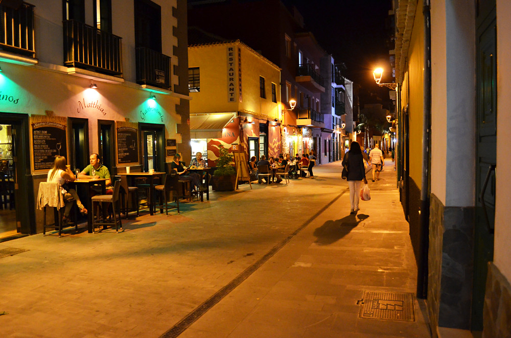 Night street scene in Tenerife with people dining and walking under warm lights