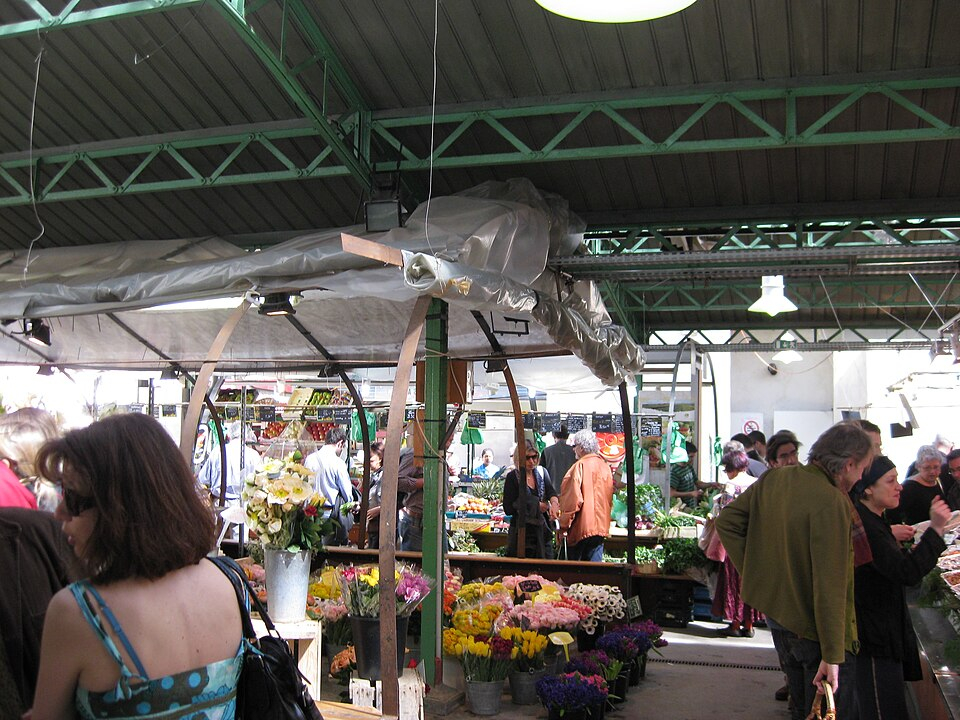 Flower stalls and shoppers inside the Marché des Enfants Rouges, photographed from Rue de Bretagne.