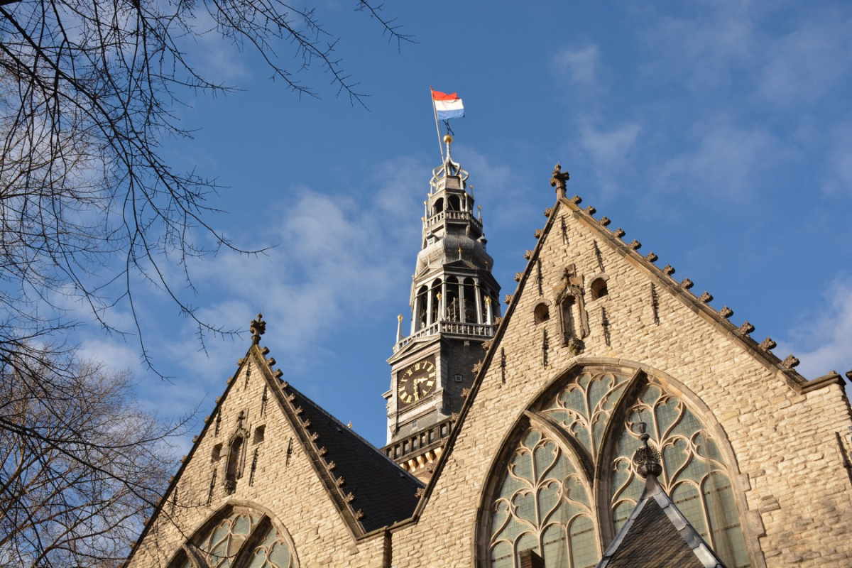 The Oude Kerk tower and church roof against a blue sky.