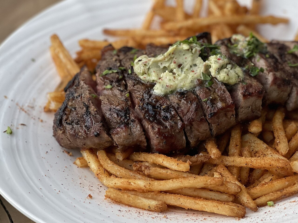 Steak frites with a herb topping, illustrating the French brasserie dish.