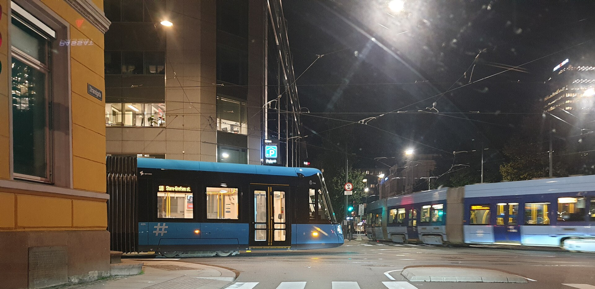 An SL18 tram at an Oslo intersection after dark.