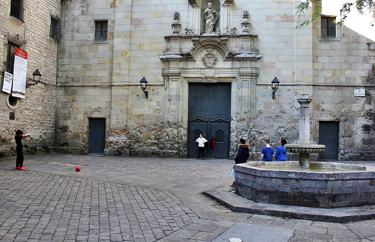 Church facade and fountain in Plaça Sant Felip Neri in Barcelona