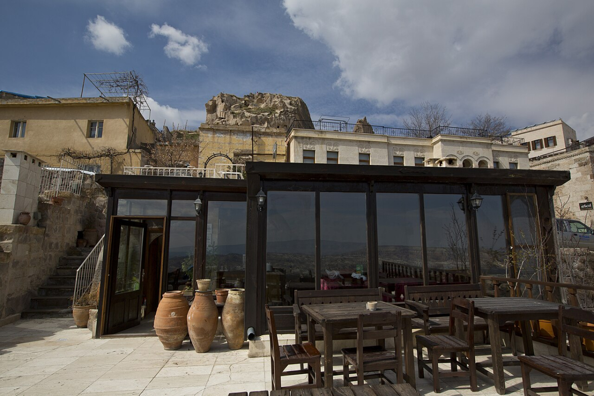 Tables on the Taka Ev hotel terrace beneath the rocky buildings of Uçhisar