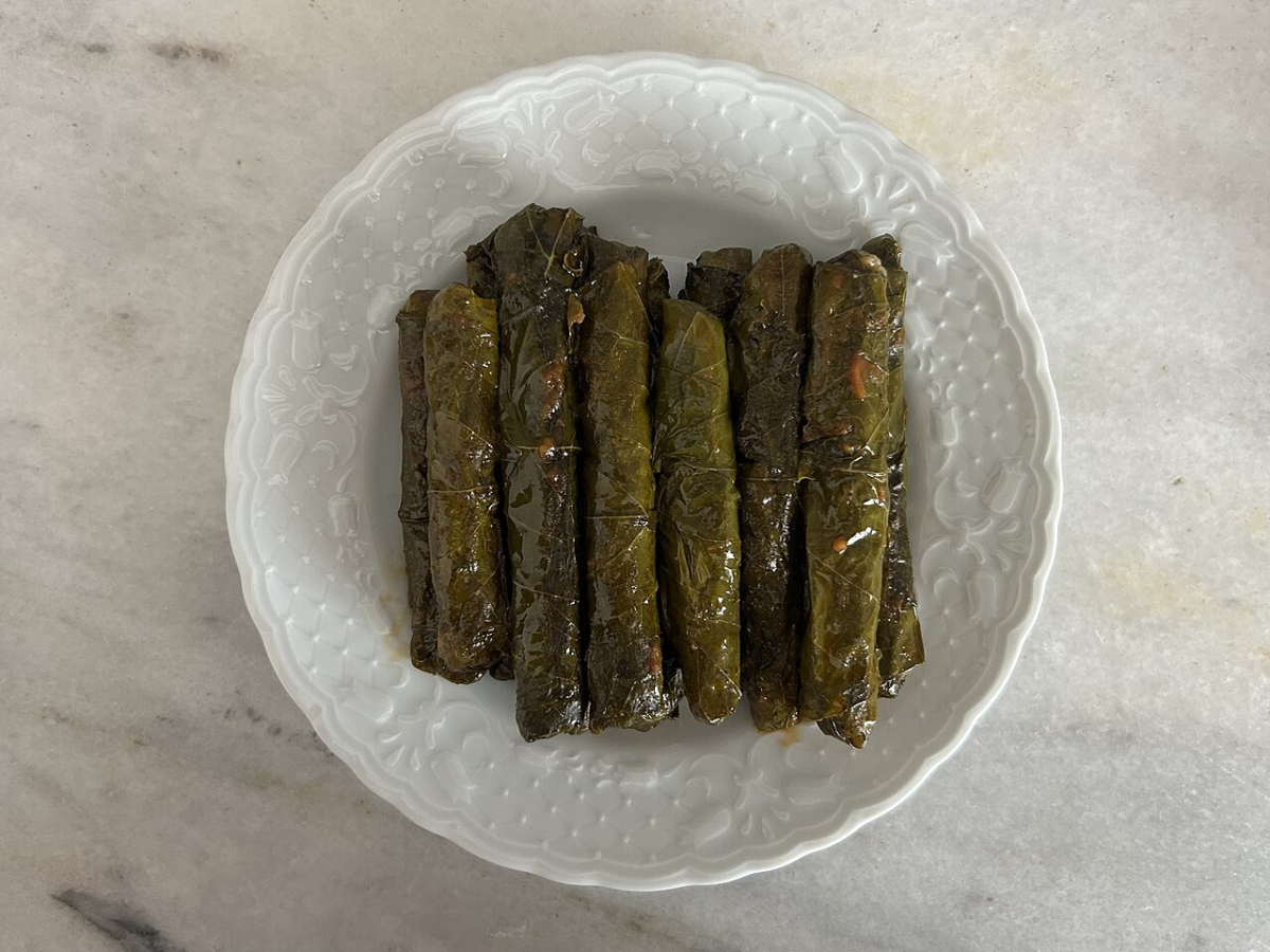 Olive-oil vine leaf rolls on a white plate