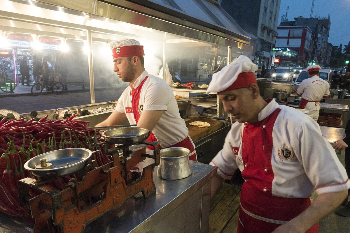 Cooks preparing Adana kebab on skewers
