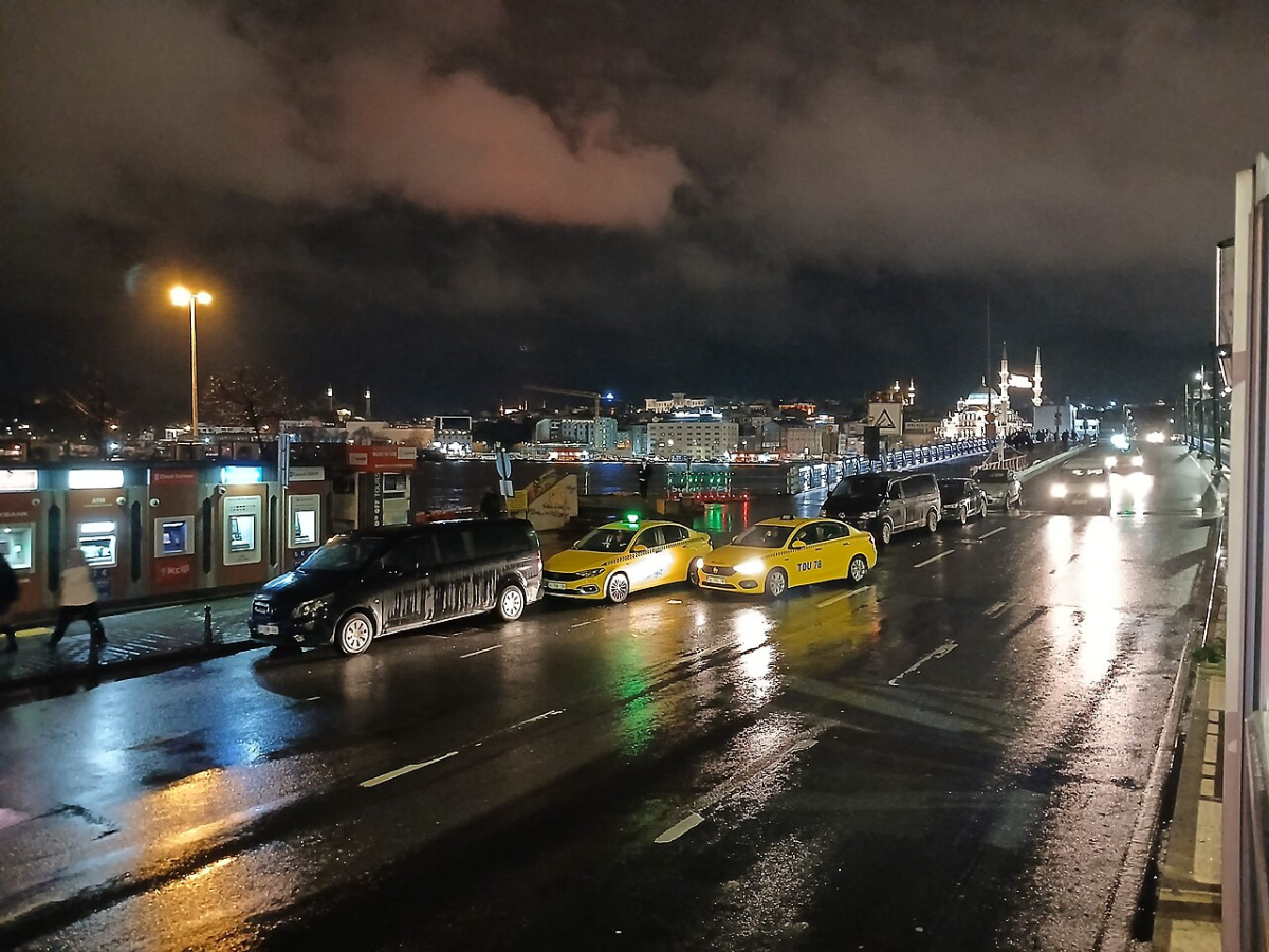 Taxis and traffic on a wet road near Galata Bridge in Istanbul at night