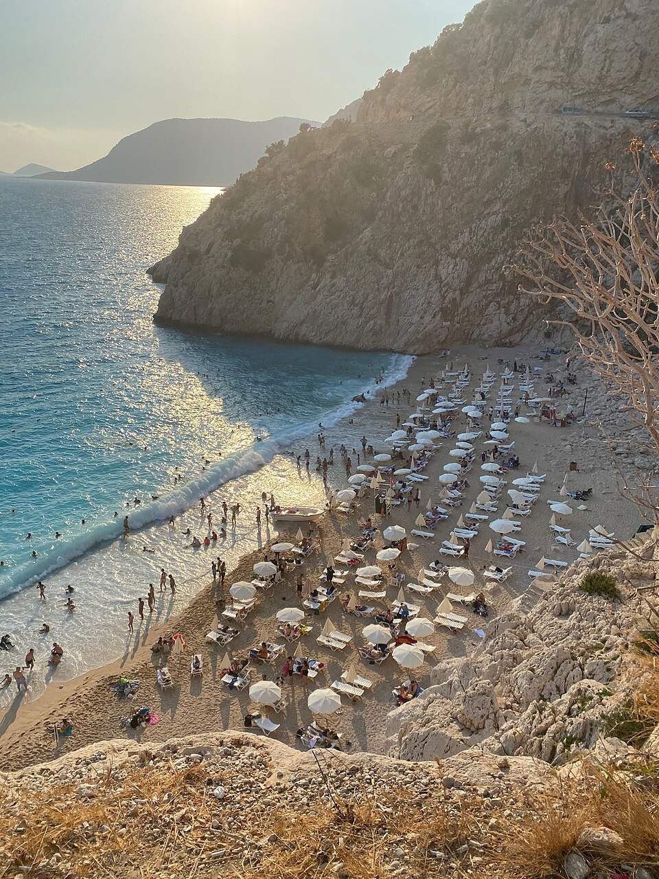 Kaputaş Beach beneath steep cliffs, with sun loungers beside the sea