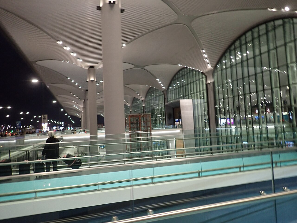 The covered entrance and glass facade of Istanbul Airport before dawn