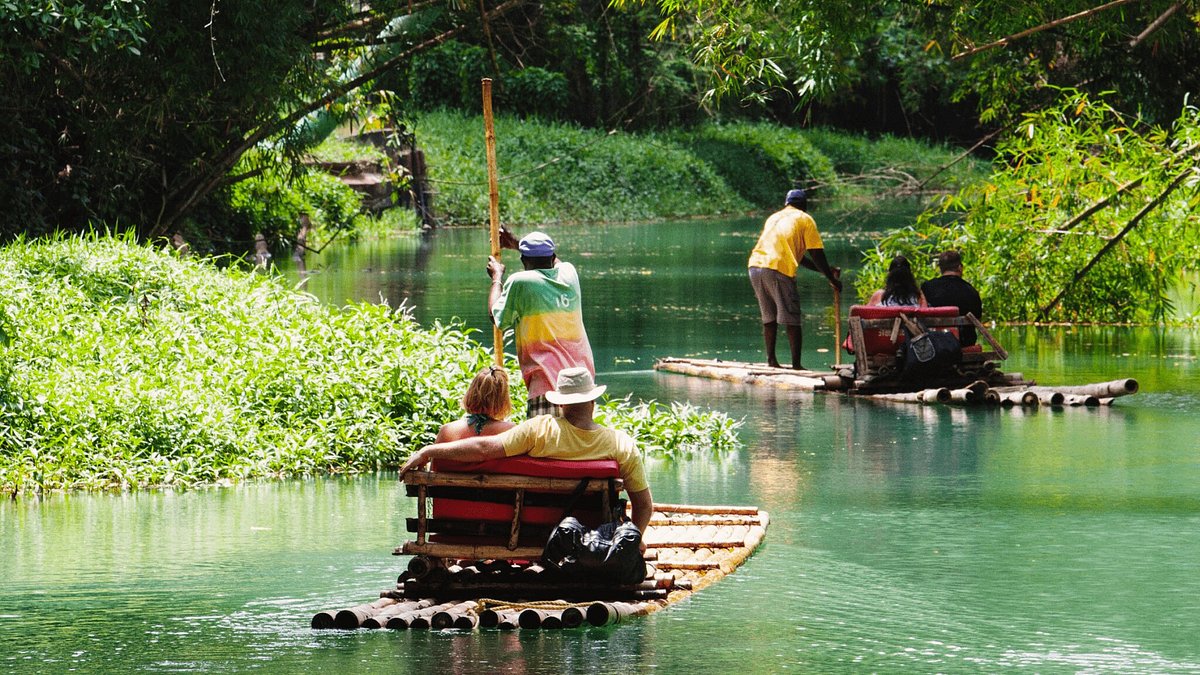 Travelers enjoying a bamboo rafting experience on a calm river in Jamaica surrounded by lush rainforest