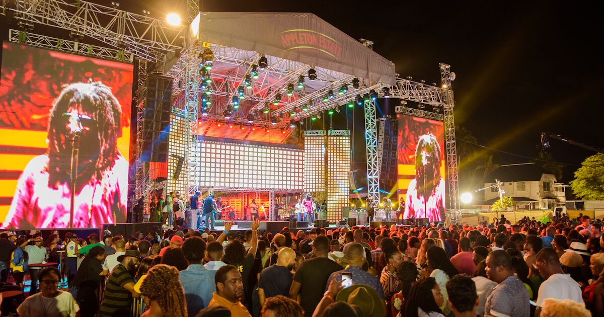Large reggae music festival in Jamaica with live stage, colorful lights and a lively crowd celebrating Jamaican culture