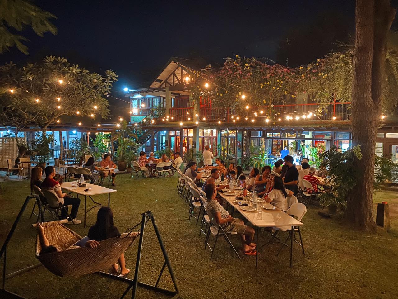 Outdoor nightlife scene in Jamaica with open-air bars, shared tables, warm lights and a relaxed evening atmosphere