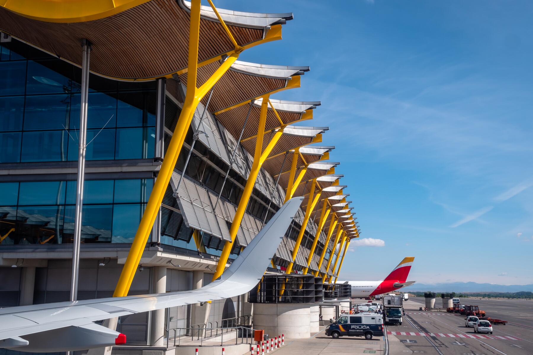 Adolfo Suárez Madrid–Barajas Airport Terminal 4 with yellow beams and aircraft wing on the apron