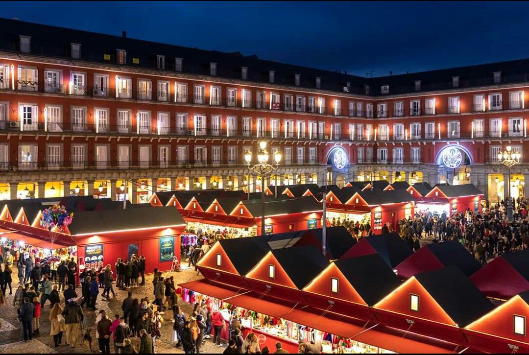Night festival market with illuminated stalls and crowds in Plaza Mayor, Madrid