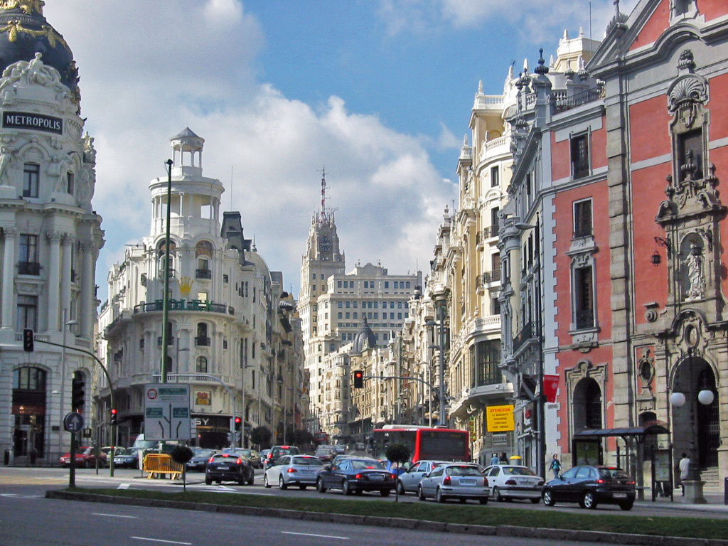 Gran Via in Madrid with historic buildings, traffic and pedestrians on a sunny day