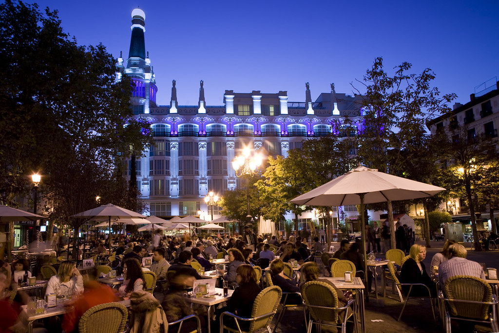 Nightlife in Madrid’s Plaza de Santa Ana with terraces, people and illuminated historic building