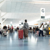 Travelers walking through a busy international airport terminal during the holiday travel season.
