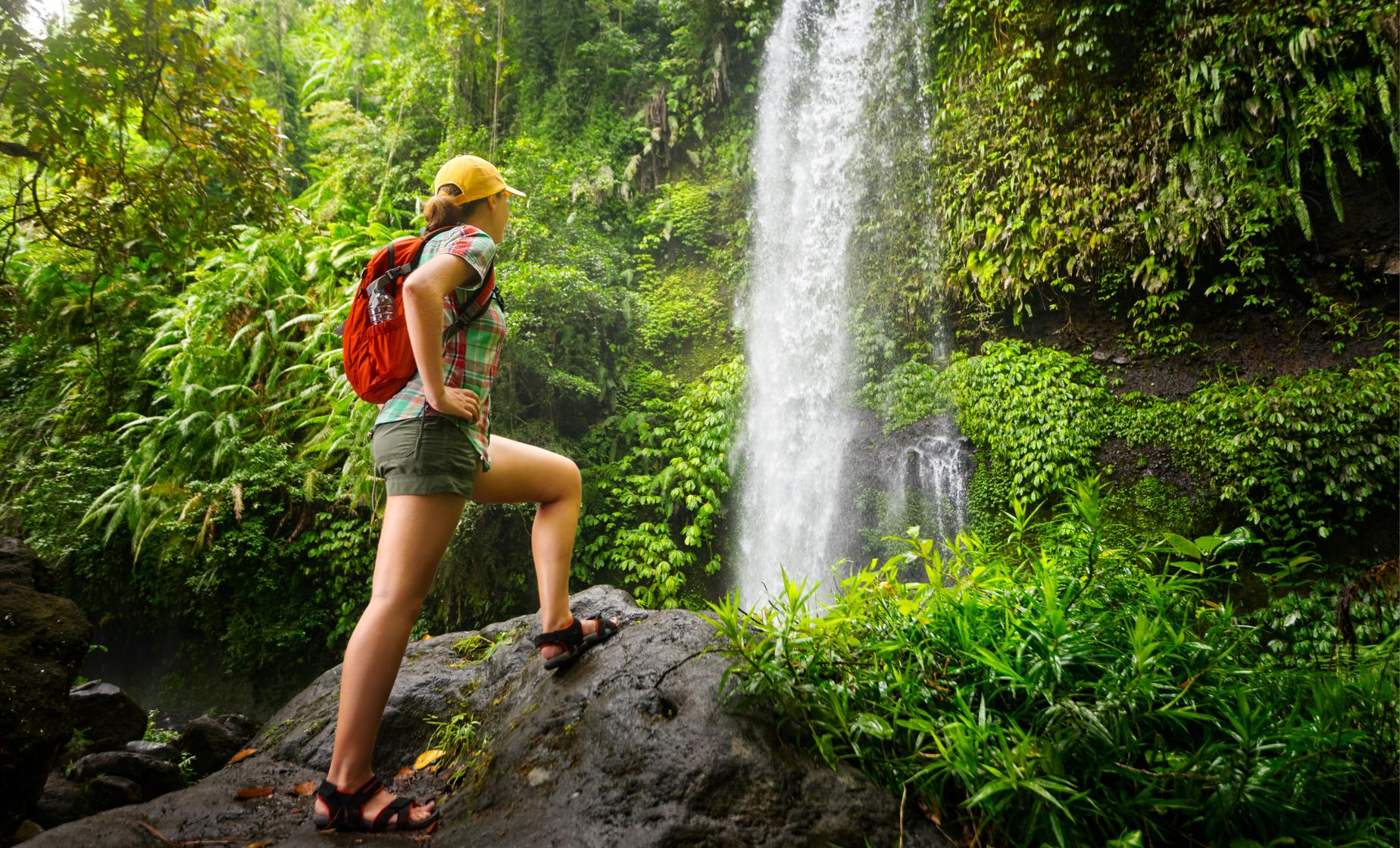 Eco-conscious traveler hiking to a waterfall in the Dominican Republic surrounded by lush rainforest vegetation