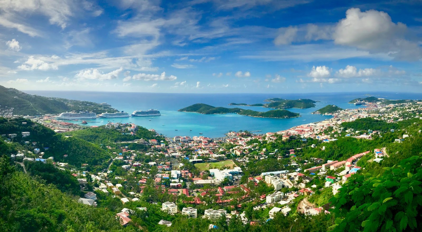 Panoramic view of the Virgin Islands showing a coastal town, green hills, and turquoise Caribbean waters